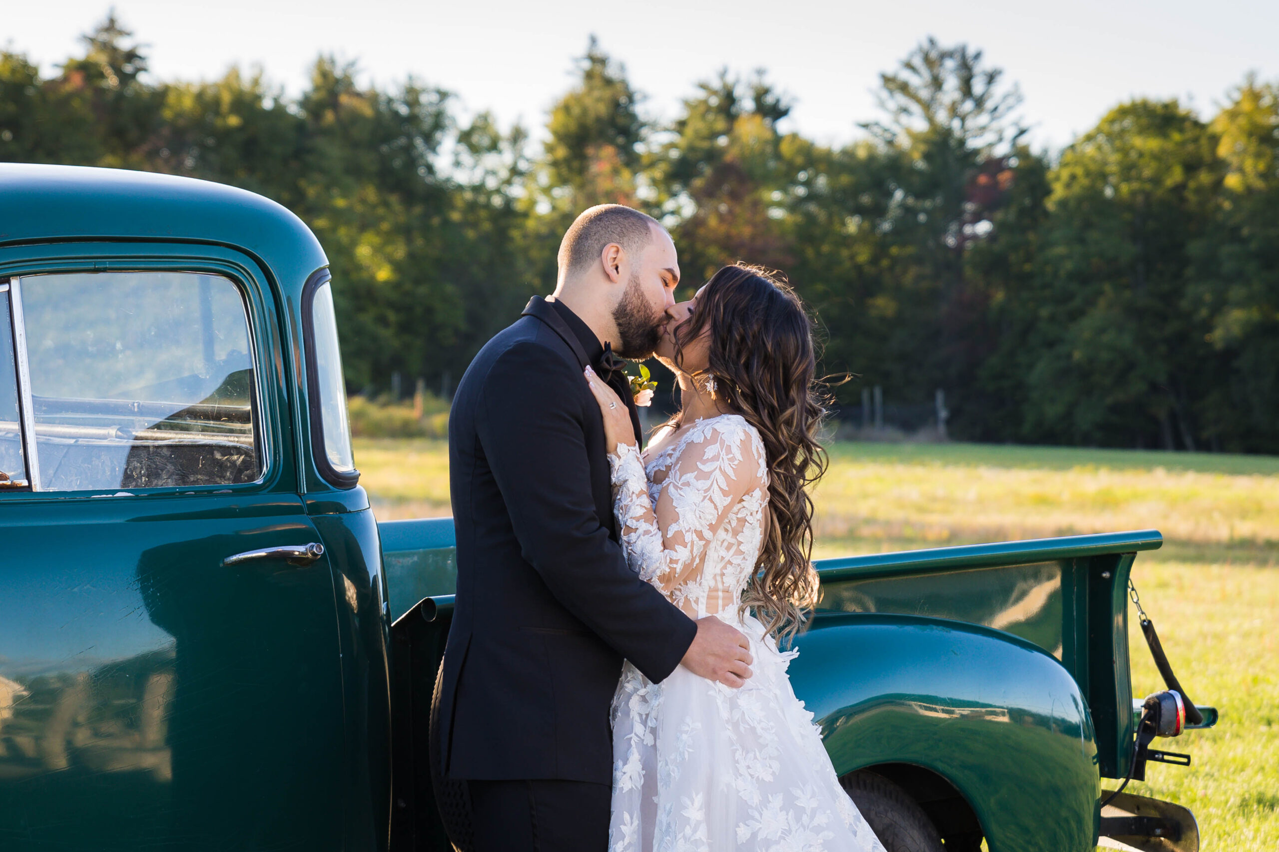 Bride and Groom kissing outdoors next to a green vintage truck