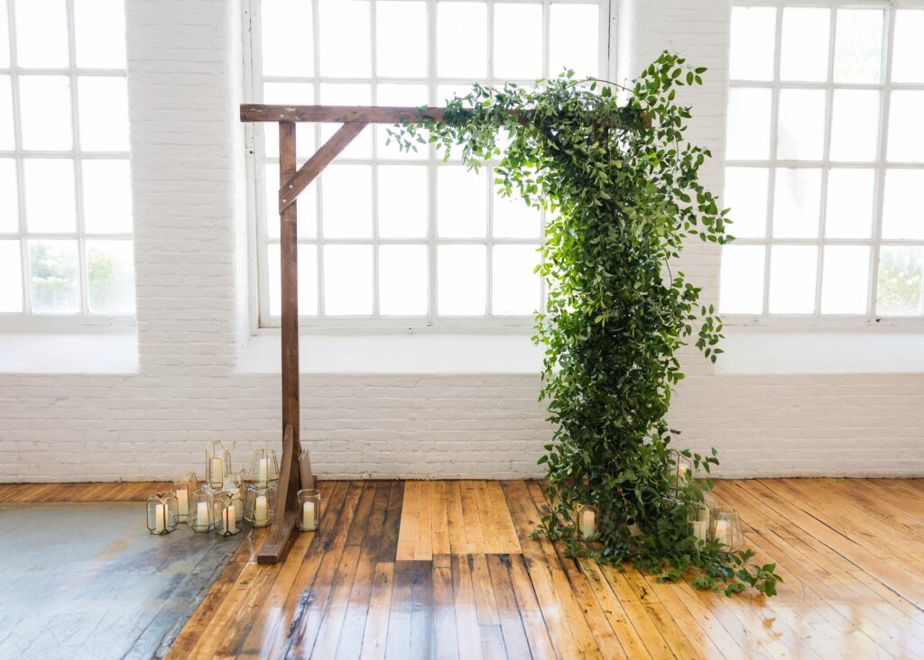 Wood Arch in Industrial Mill for a wedding with Greenery and candles surrounding it at the Boylston rooms