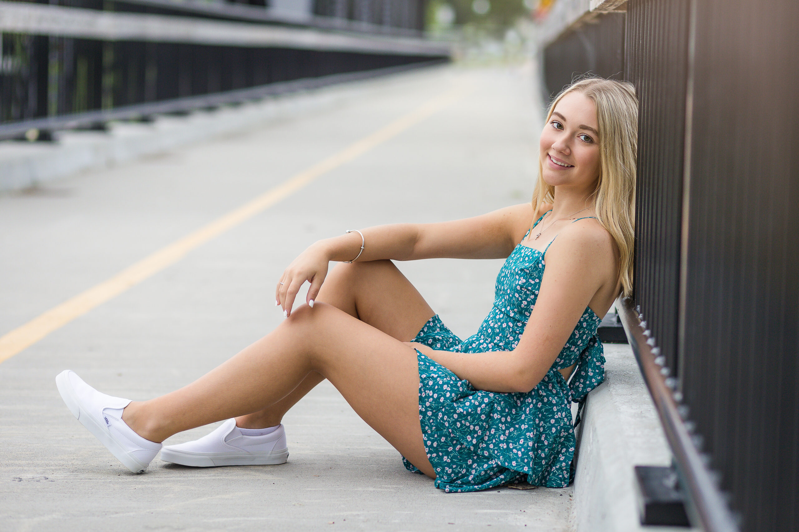 High School Senior Sitting on a bridge with blonde hair and green dress
